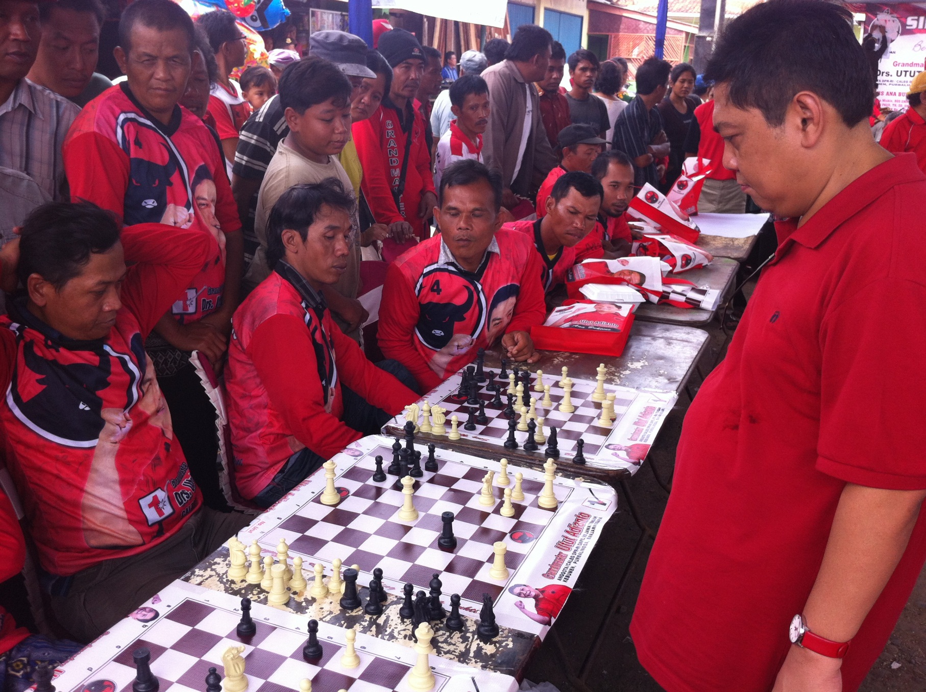 Utut prepares his next move against a local player. Several defeated challengers and a sizeable crowd look on - Tom Power 5. Power 3